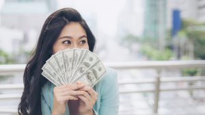 Successful beautiful asian business young woman holding money US dollar bills in hand , business concept