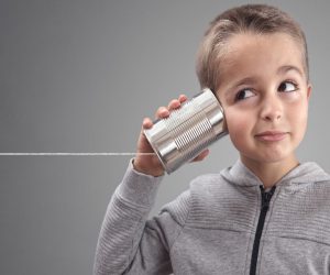 Boy on tin can phone listening to curious good news