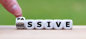 Hand turns a dice and changes the word “passive” to “aggressive”, or vice versa.