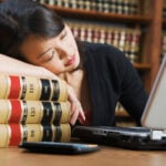 Asian woman sleeping on stack of library books