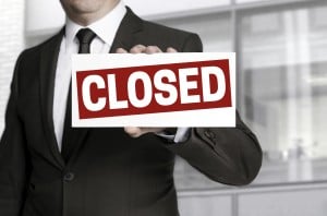 Businessman holding closed sign to viewer