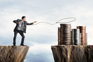Businessman Attempting To Lasso A Stack Of Coins