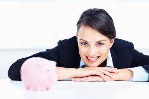 Happy business woman with a piggy bank at table