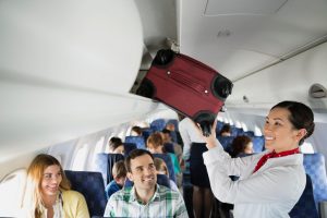 Flight attendant putting luggage in overhead bin in airplane