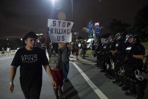 TOPSHOT - Protesters walk past riot police blocking off a ramp to a highway during a demonstration against police brutality in Charlotte, North Carolina, on September 22, 2016 following the shooting of Keith Lamont Scott by police two days earlier and two nights of riots. Hundreds of protesters defied a midnight (0400 GMT) curfew Friday and continued demonstrations in Charlotte, North Carolina over the fatal police shooting of a black man. / AFP / NICHOLAS KAMM        (Photo credit should read NICHOLAS KAMM/AFP/Getty Images)