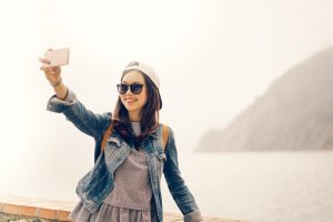 Asian traveler taking selfie with ocean view, soft warm tone