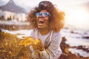 Afro hipster girl laughing ecstatically while throwing gold glitter