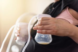 Mother pumped milk from both boobs into Automatic breast pump machine. mom milk is the best healthy nutrition food for newborn baby. Motherhood and Child infant Healthcare