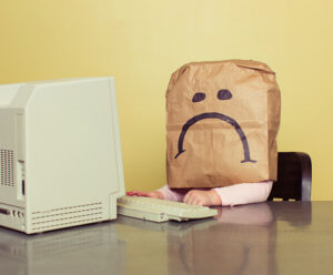 Young Girl in Front of Computer with Brown Bag Frown