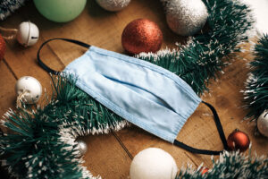 Respiratory protective mask in the middle of Christmas decoration. Wooden Table, Christmas balls and garland. Daylight.