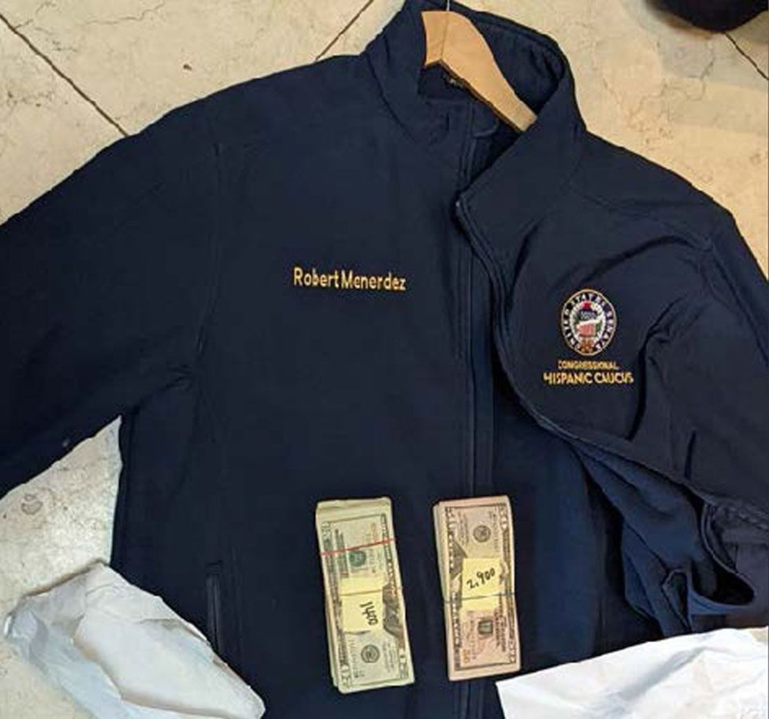 Image from indictment, showing two banded stacks of cash on a blue windbreaker with the name Robert Mendez on it, along with senate seal and Congressional Hispanic Caucus.