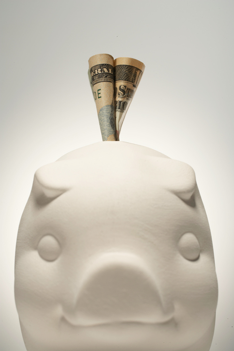 US paper currency sticking out of piggy bank