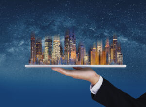 Real estate business, smart city, and building technology. Businessman hand holding digital tablet with buildings hologram and stars background