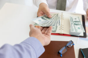 Business and finance concept, Hand of a businessman giving money to his partner.