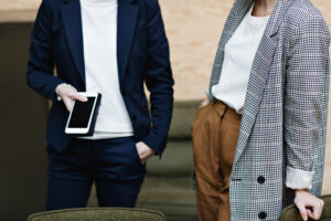 Midsection of businesswoman holding mobile phone while standing with female professional at office