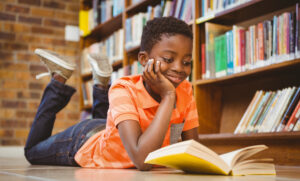 Cute boy reading book in library